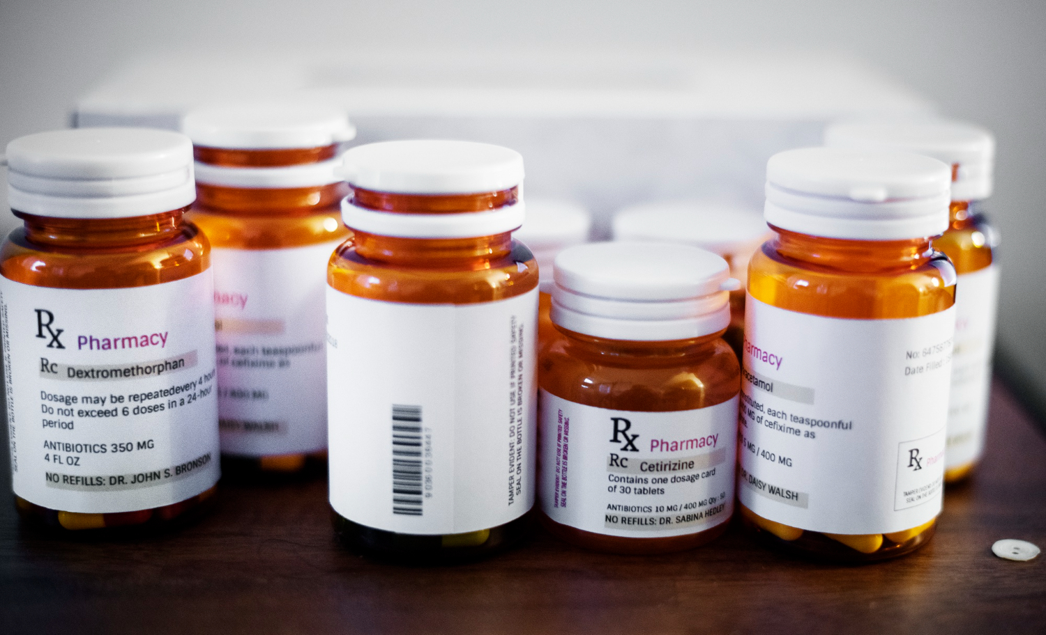 Clear brown prescription bottles with white caps and white labels, containing the name of the medication and dosage information.