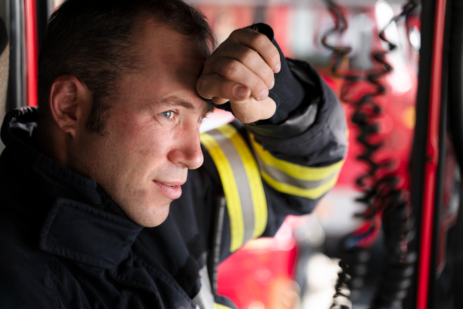 An EMS professional rests his head against his arm, looking tired after a call.