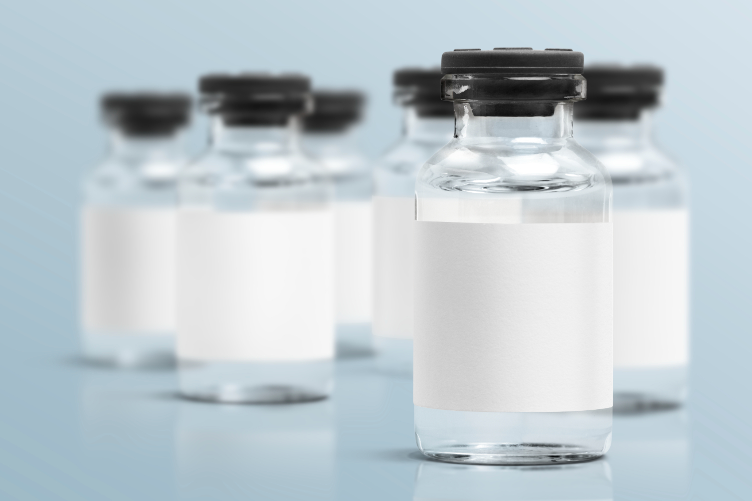 A close up image of liquid medicine vials against a greyish blue background.